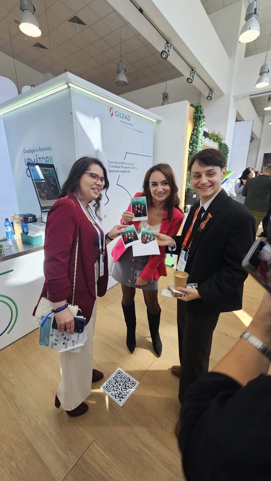 Top Shots pentru Gilead la Congresul Național de Oncologie 2026 14 Trei participante arată fotografiile printate pe loc la activarea Top Shots Gilead